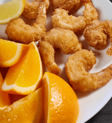fried shrimp platter of seven on a plate with orange slices